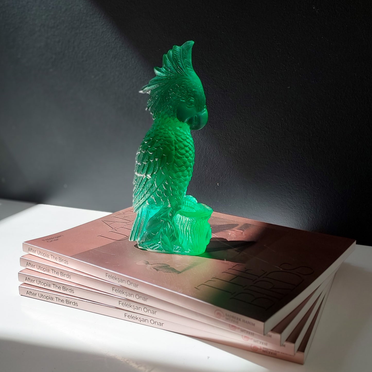 Rio Parrot Cast Glass Sculpture Emerald Green on stack of books