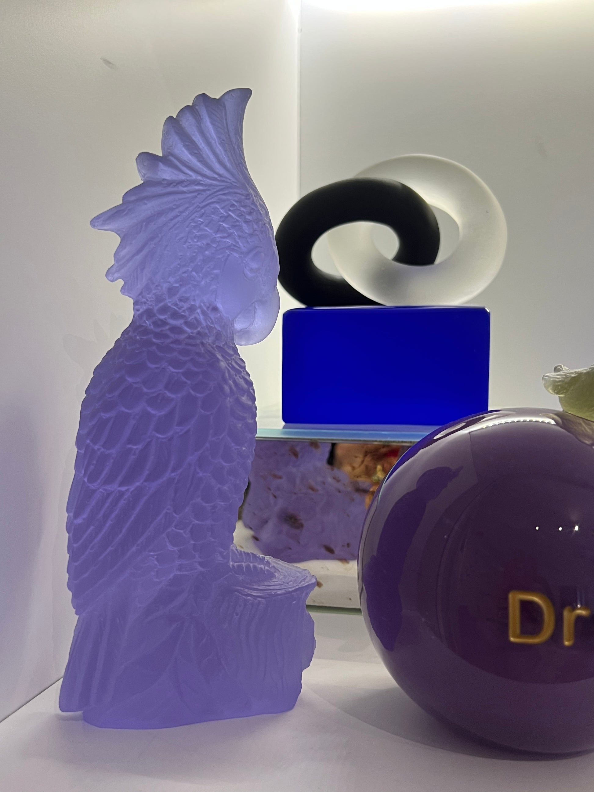 Rio Parrot Cast Glass Sculpture Lilac next to message on a ball